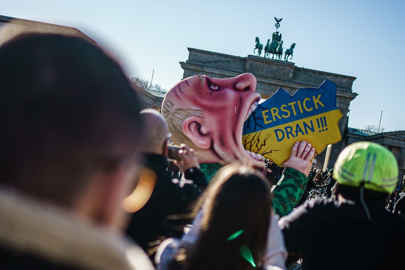 „Îneacă-te!" scrie pe o pancartă cu o caricatură a lui Vladimir Putin la un protest în fața Portții Brandenburg din Berlin, pe 12 martie 2022. Foto: EPA