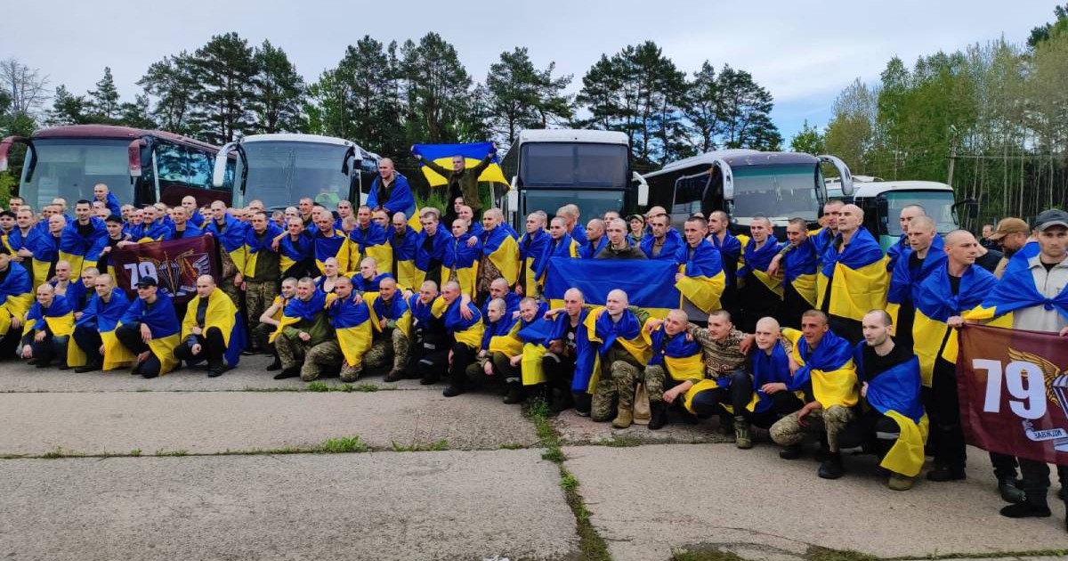 Poză cu soldații ucraineni eliberați marți, 6 mai, în cadrul schimbului de prizonieri dintre Rusia și Ucraina. Țin în mâini steaguri ale Ucrainei și sunt așezați în fața a cinci autocare