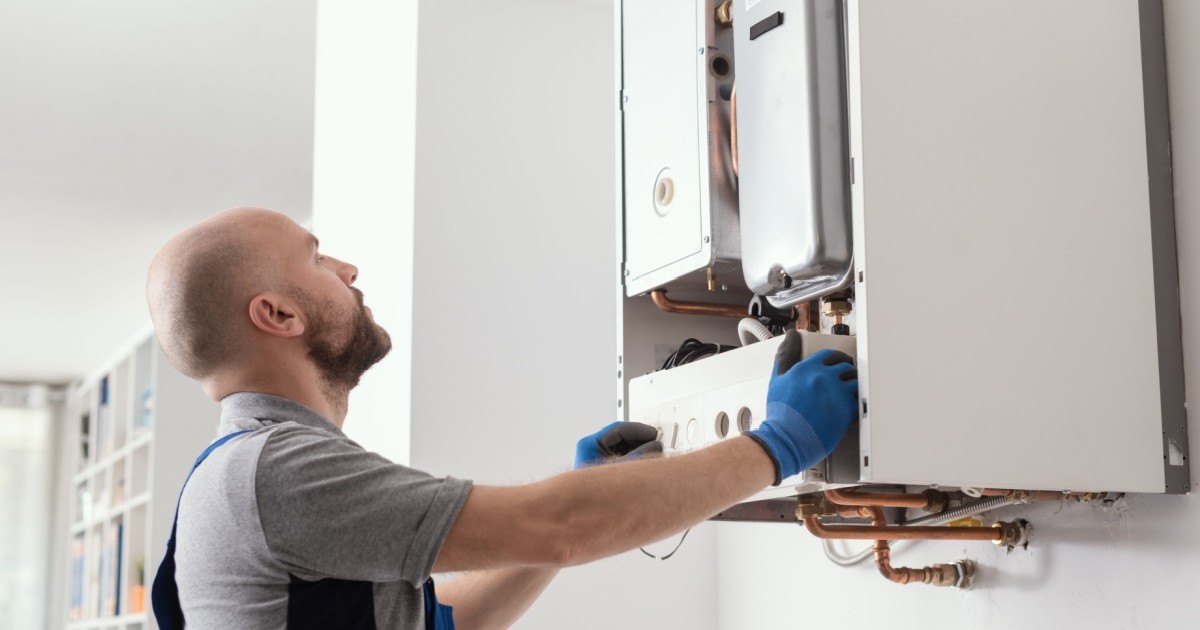 Un instalator fixează o centrală de apartament pe peretele unei camere