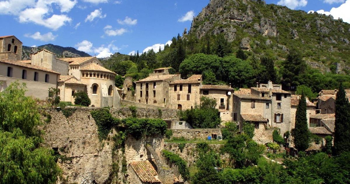 Căsuțe ascunse printre vegetație pe o colină din satul Saint-Guilhem-le-Désert