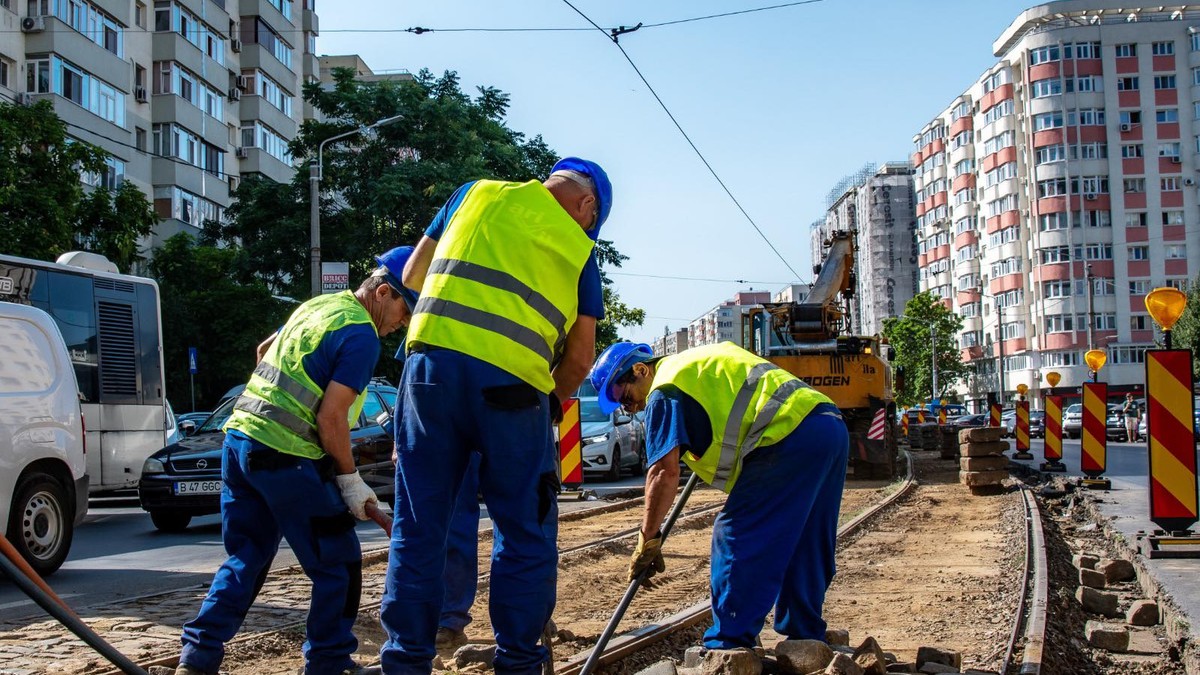 Trei muncitori lucrează la reabilitarea unei linii de tramvai din București, august 2025