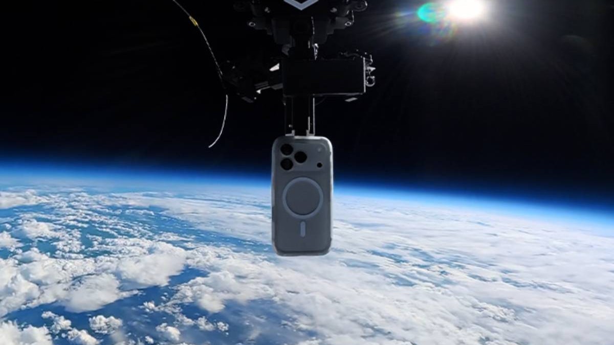 Un iPhone 17 Pro protejat de o husă este suspendat la mare altitudine, deasupra Pământului, înaintea testului de cădere din stratosferă. În fundal se vede curbura planetei, acoperită de nori, iar telefonul este prins de mecanismul balonului folosit în experiment.