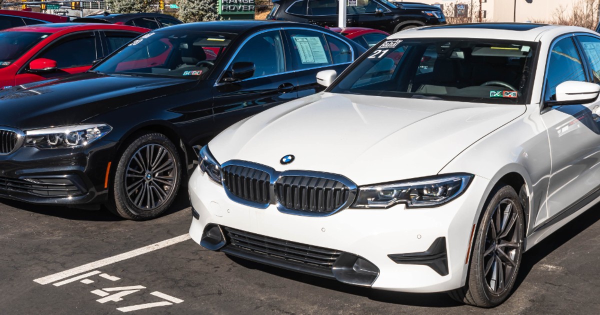 Mai multe automobile BMW sunt expuse într-un parc auto, pregătite pentru vânzare. Imaginea ilustrează piața mașinilor second-hand și procesul de achiziție a unui vehicul de la un dealer auto.