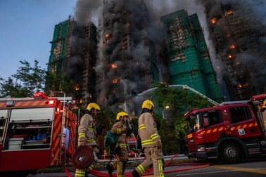 November 26, 2025, Hong Kong, Hong Kong: Emergency vehicles parked in a road where Smoke and flames rise as a major fire engulfs several residential buildings at Wang Fuk Court on November 26, 2025 in Hong Kong. Serval residential building in Wang Fuk Court located in Tai Po District caught fire today, the Hong Kong Fire Department has issued the No.5 fire alarm, the fire at local time 1800 has claimed the life of one firefighter and three other people.,Image: 1054735849, License: Rights-managed, Restrictions: , Model Release: no