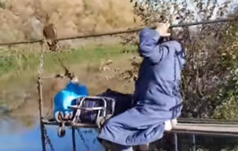 Femeie înregistrată când trece Mureșul pe un troliu ca să meargă la piață. Autorul filmării spune că e o bătrână de 94 de ani