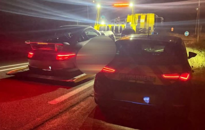 O mașină pe care scrie Gendarmerie oprită pe marginea drumului lângă o platformă de tractare pe care se află o mașină neagră