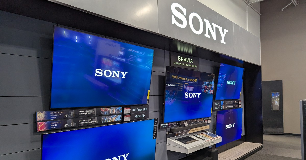 Imaginea arată un stand de magazin dedicat televizoarelor Sony, unde sunt expuse mai multe modele mari, cu ecrane aprinse și logo-ul brandului vizibil. Amenajarea modernă și panourile informative sugerează o zonă de prezentare premium, destinată testării și comparării televizoarelor.