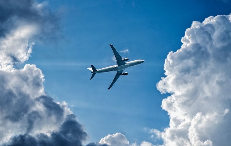 Un avion zburând prin cerul albastru și printre nori