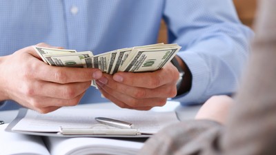 The,Businessman,Considers,Cash,Dollars,In,The,Office,Issues,Salaries