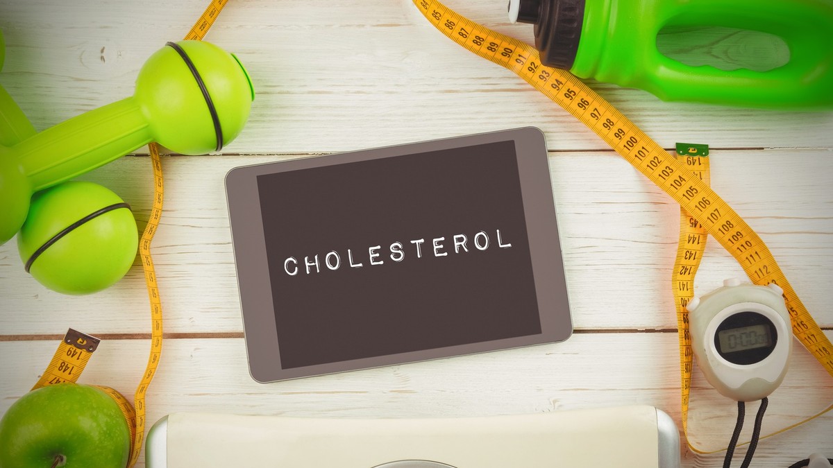 Imagine cu o tabletă pe care scrie colesterol, un centimetru, un măr verde și un cântar.