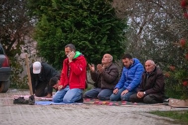 Mai mulți bărbați se roagă în fața moscheei