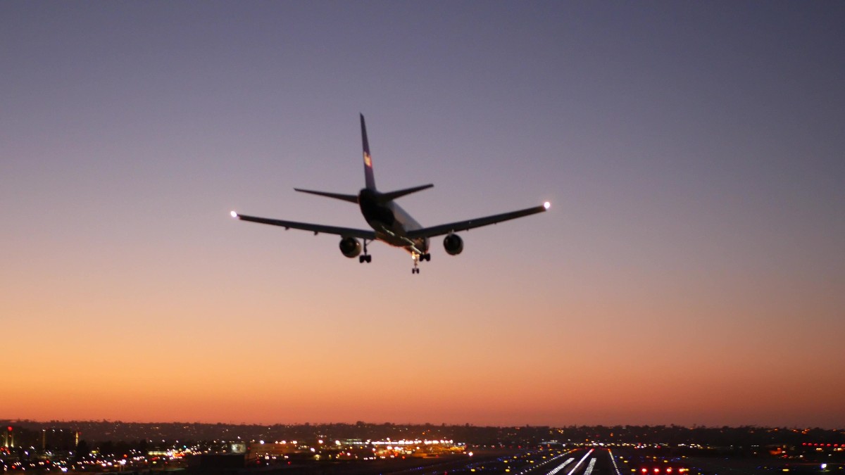 Un avion în timp ce aterizează, pe fundalul unui apus