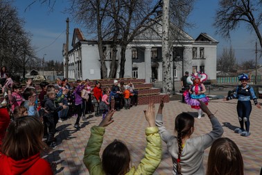Copiii din Volnovakha se bucură de vremea caldă jucându-se în fața unei clădiri distruse din centrul orașului | Foto: EPA