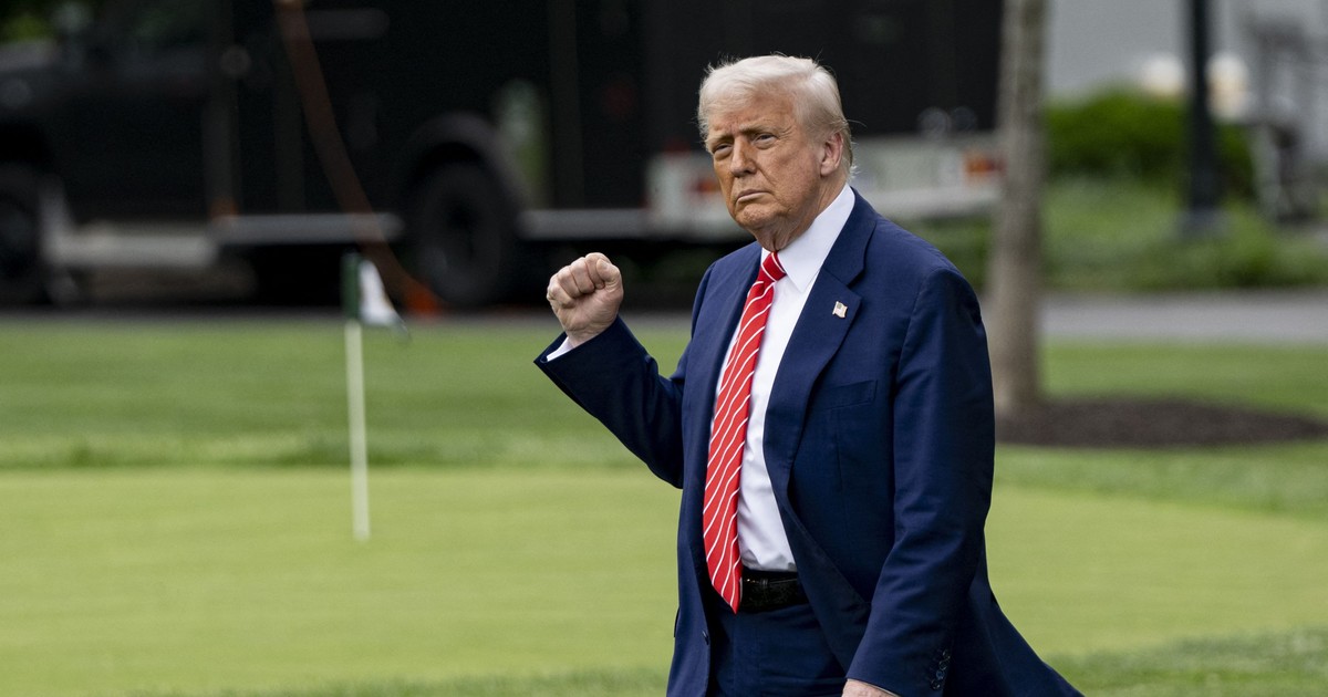 Donald Trump surprins în timp ce ține pumnul strâns. Poartă un costum albastru, cu cămașă albă și cravată roșie