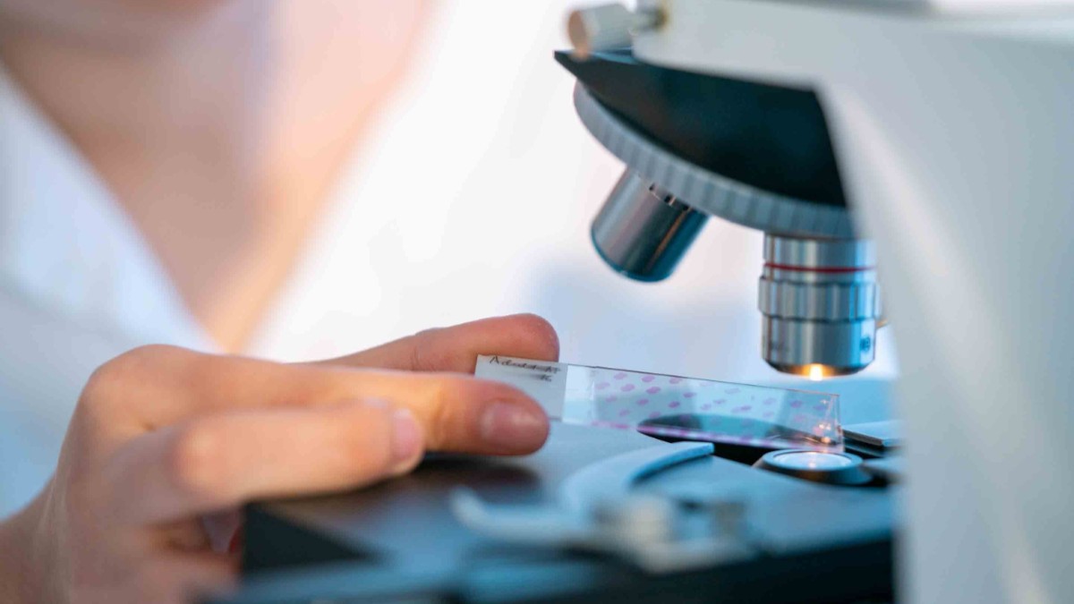O femeie în timp ce face o cercetare la microscop