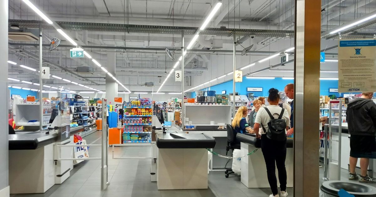 Intrarea într-un magazin Action unde se văd casele de marcat și oameni care plătesc cumpărăturile