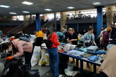 În centru dreapta, cu bluză neagră, prefectul Capitalei ajută la sortarea hainelor.
