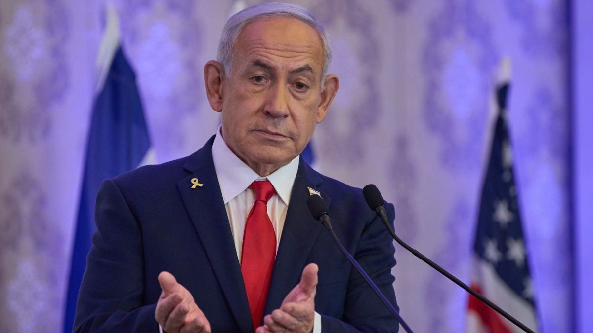Prim-ministrul israelian Benjamin Netanyahu, în sacou negru, camasa alba si cravata rosie, tine maine in fata, impreunate, si palmele deschise, in timp ce vorbește la o conferință de la Ierusalim, duminică, 27 iulie 2025.