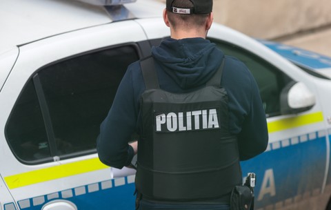 Un polițist cu vestă antiglonț, în timp ce încearcă să deschidă ușa unei mașini de Poliție