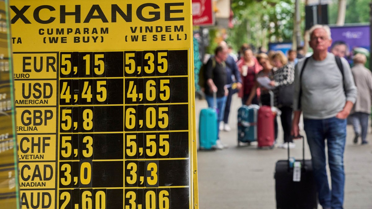 Oamenii trec pe lângă un panou de schimb valutar care afișează euro care crește la 5,35 lei, la o casă de schimb valutar din centrul Bucureștiului