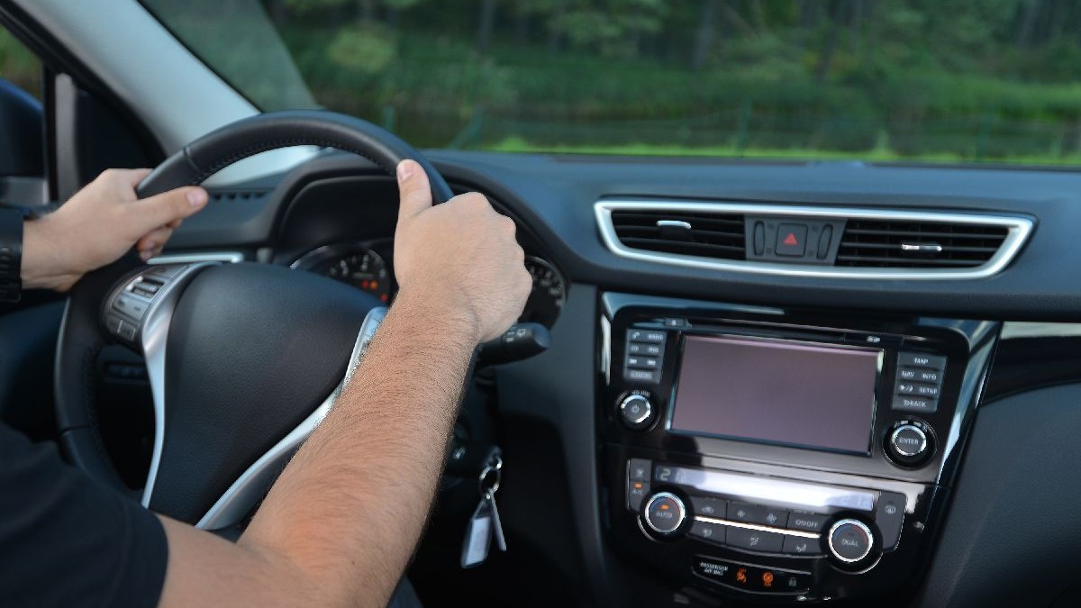 Bărbat aflat într-un autoturism cu mâinele pe volan