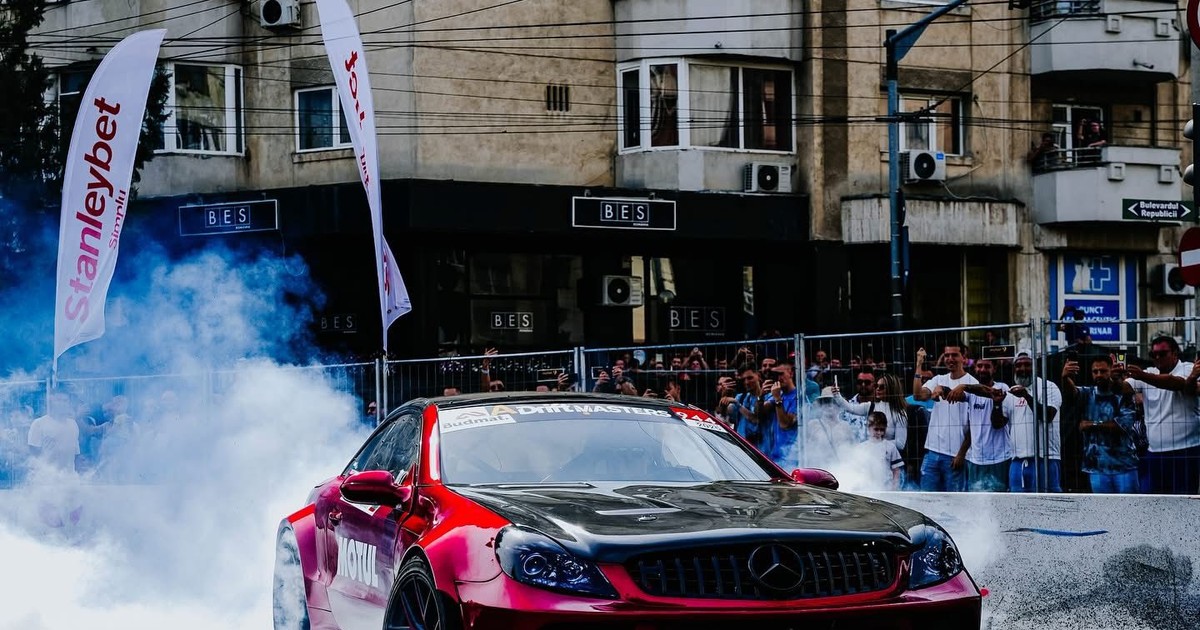 o masina de cursede culoare rosu metalizat cu dungi negre in etapa finală a Campionatului Național de Drift