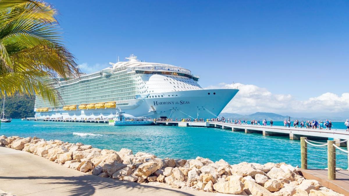 Un vas de croazieră ancorat în port, iar turiștii coboară pentru a vizita insula