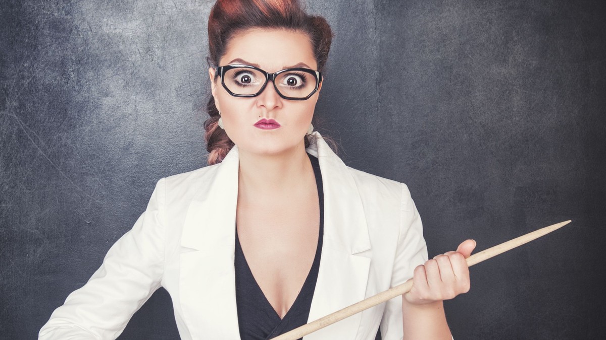Profesoara nervoasă care ține amenințător un băț în mână