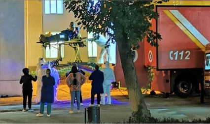 Pacientul e ridicat, cu targa, la peste 2,5 metri pentru a fi băgat în TIR-ul ATI. Două cadre medicale în combinezoane asigură targa în momentul operațiunii