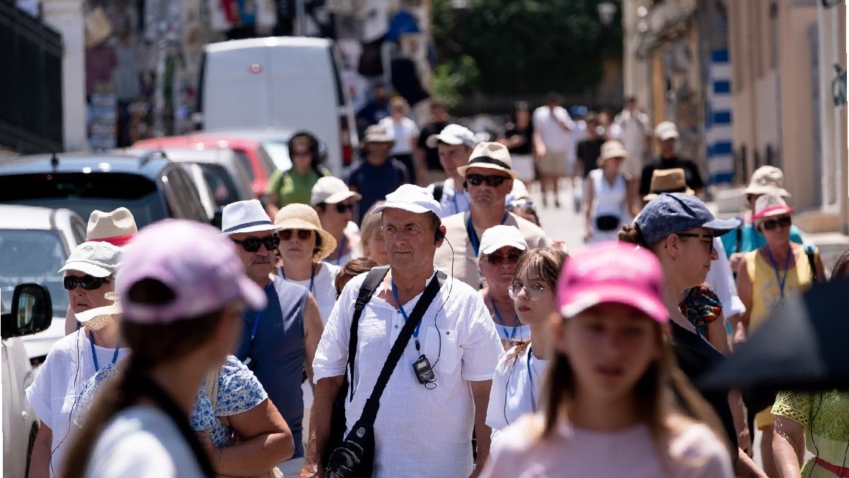 Un grup de turiști poartă pălării în centrul Atenei, Grecia, pe 16 iulie 2025. Vizitatorii explorează orașul sub soarele arzător.