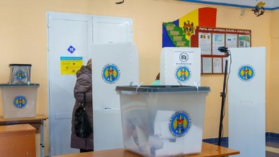 O femeie voteazî într-o secție de votare din Republica Moldova, unde sunt mai multe cabine de vot și urne pentru voturi