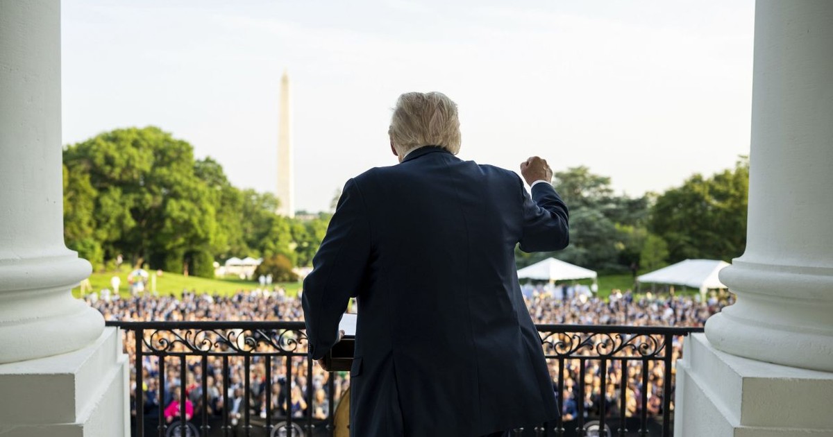 Donald Trump ridică pumnul de pe treptele Casei Albe, văzut din spate.