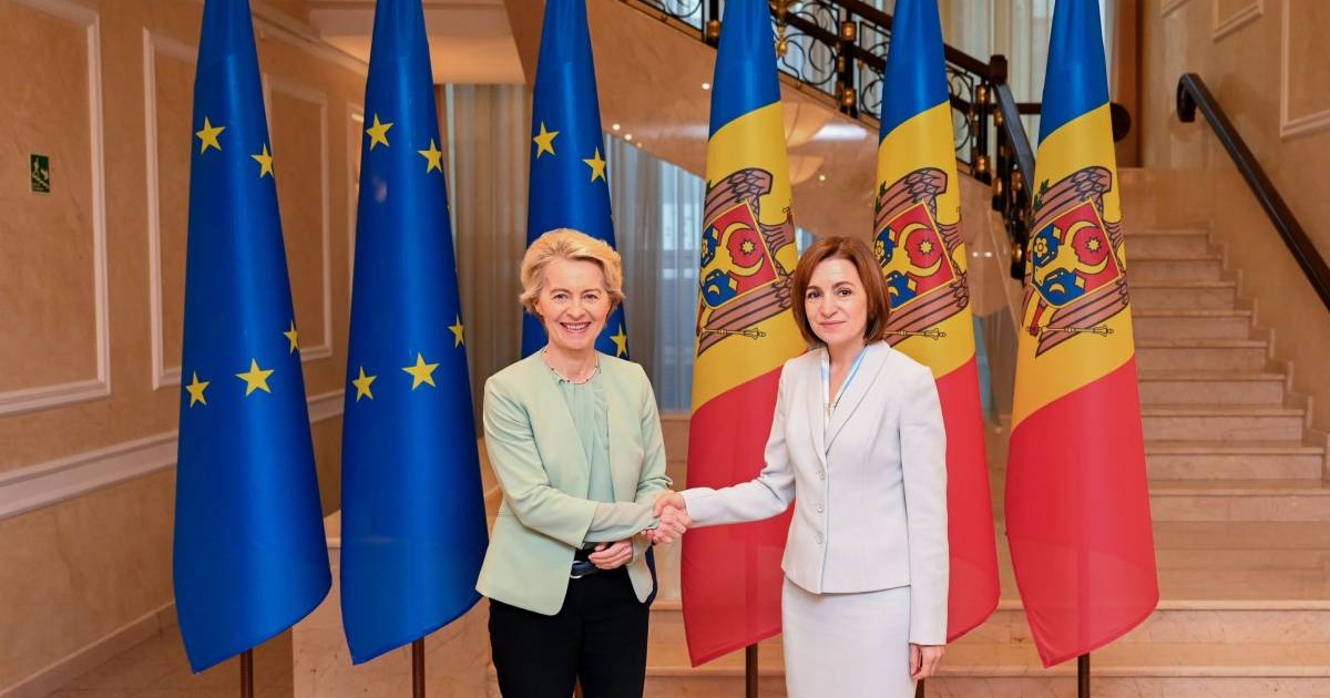 Maia Sandu și Ursula von der Leyen la Chișinău, în timpul unei vizite ofiaile. Șefa Comisiei Europene și președintele Republicii Moldova dau mâna și zâmbesc, iar în spaele lor sunt steagurile UE și steagul Republicii Moldova