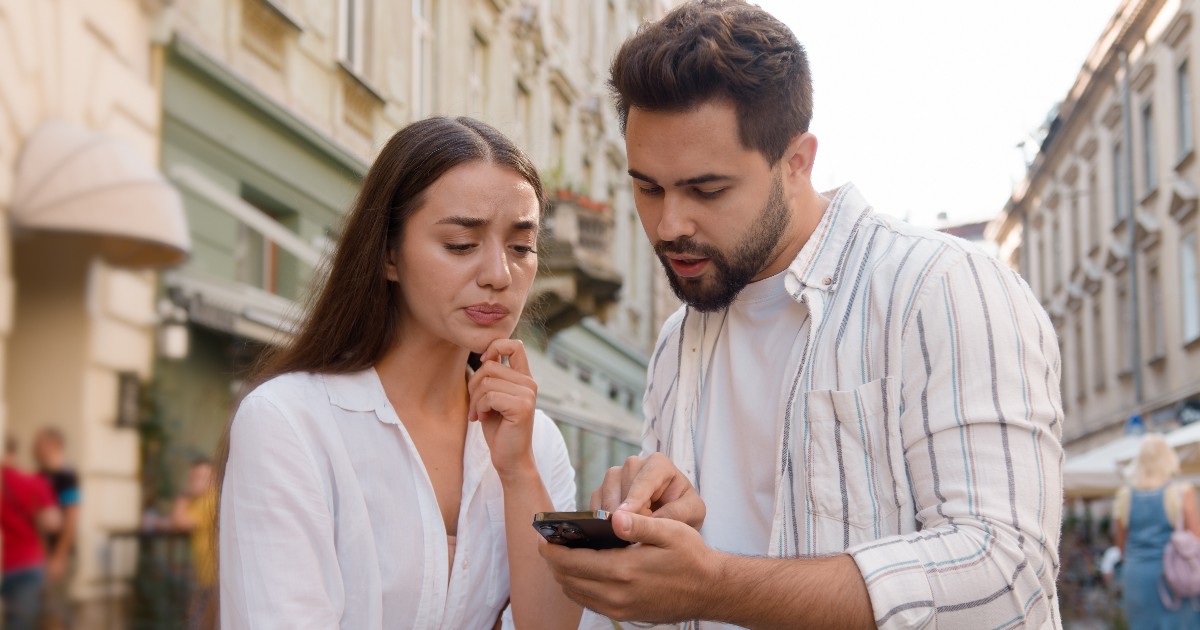 Un bărbat care îi arată lucruri pe telefon unei femei.