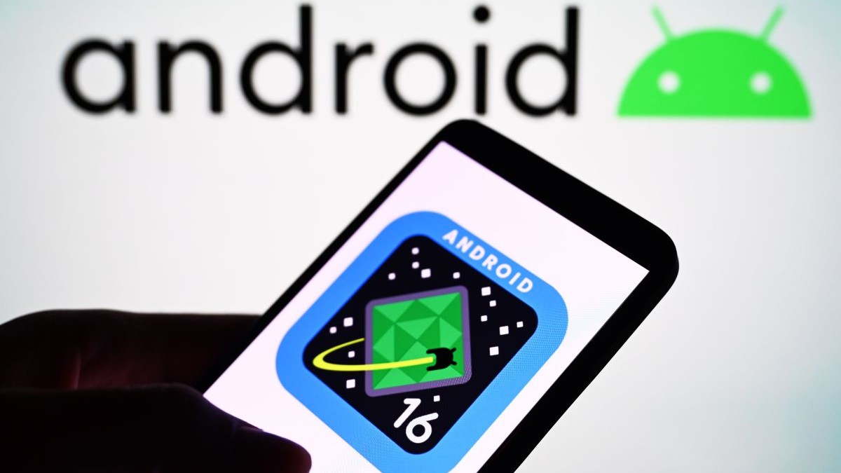 Ilustrație care reprezintă logo-ul sistemului de operare Google Android 16, pe ecranul unui telefon ținut în mână în fața unui fundal alb spre gri.