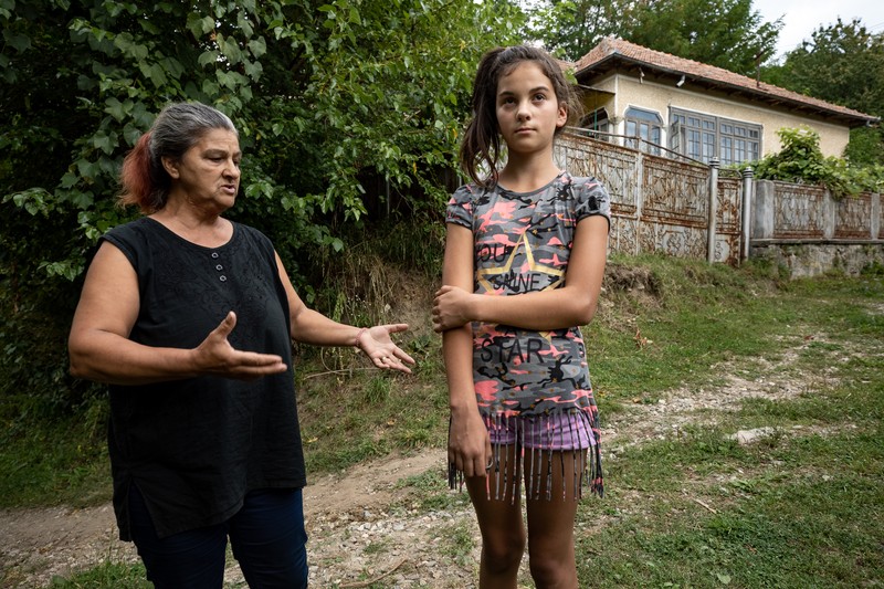 Nina şi Luciana stau pe drumul neasfaltat care duce la casa lor