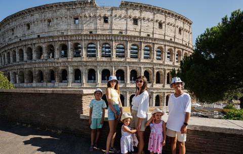 O mamă cu cinci copii pozează având Colosseumul ca fundal, în centrul istoric al orașului Roma, Italia.