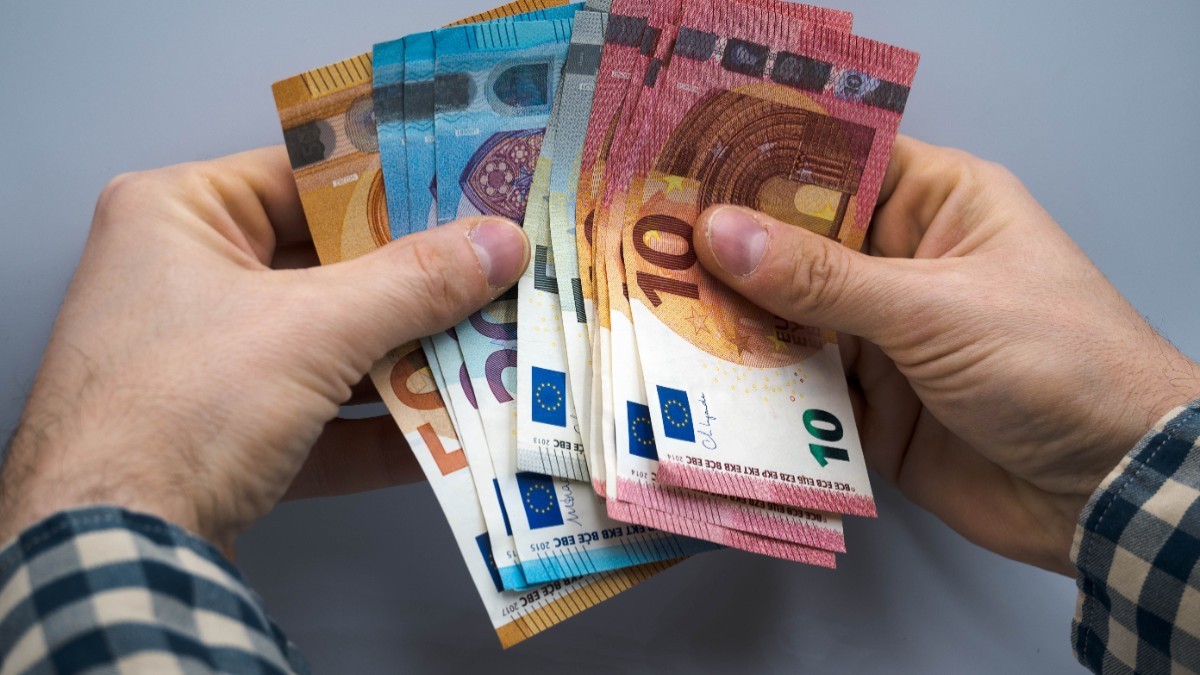Un bărbat care ține mai multe bancnote de euro 