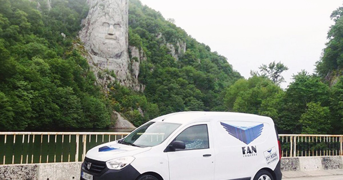 Fan Courier vrea să ”importe” șoferi din Basarabia, Ucraina sau Serbia din cauza crizei de forță de muncă, în special în Transilvania. Mașină Fan Courier în fața stâncii sculptate cu chipul lui Decebal de la Porțile de Fier