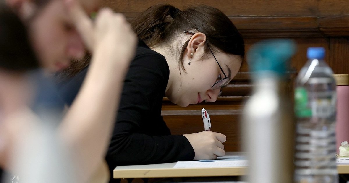 O elevă în prim plan, scrie pe o foiae, in imagine se vad sticle de apa. - Elevii susțin proba de filosofie în cadrul examenelor de bacalaureat, prima sesiune de testare a bacalaureatului 2024 (examen de absolvire a liceului) la liceul Fustel de Coulanges din Strasbourg, estul Franței, pe 18 iunie 2024.