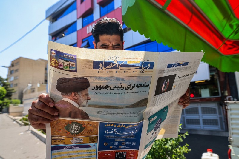 A man reads a newspaper with a front-page report on the crash of the Iranian president's helicopter outside a kiosk in Tehran on May 20, 2024. Iranian President Ebrahim Raisi was declared dead on May 20 after rescue teams found his crashed helicopter in a fog-shrouded western mountain region, sparking mourning in the Islamic republic.,Image: 874709013, License: Rights-managed, Restrictions: , Model Release: no