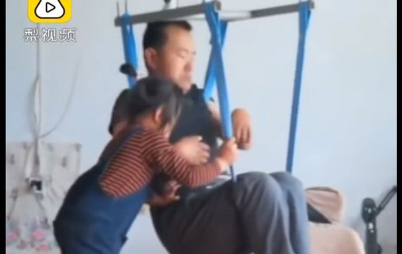 VIDEO | Imagini emoționante cu o fetiță care are grijă de tatăl ei paralizat. Bărbatul a fost părăsit de soție la două luni după ce a aflat că nu mai poate să se miște