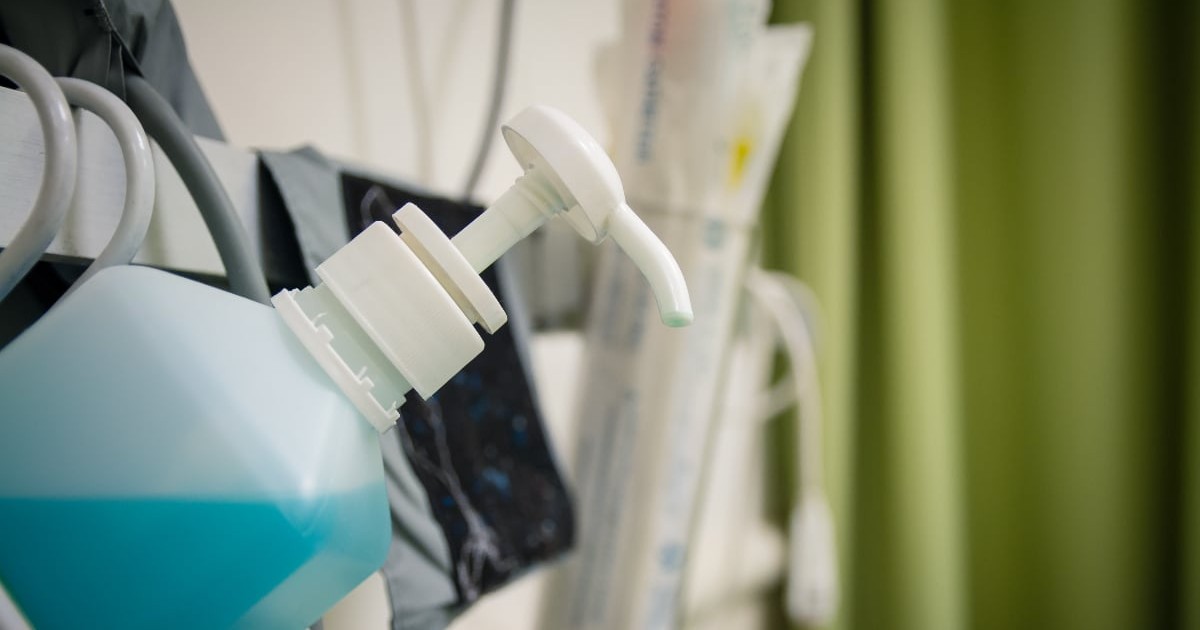 Imaginea ilustrează un recipient cu antiseptic într-un cadru medical de spital