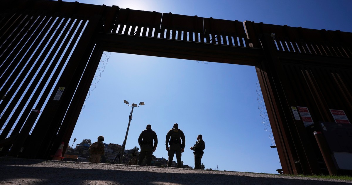 Agenți de poliție surprinși în interiorul unei porți a unuia dintre cele două ziduri de frontieră care separă Mexicul de Statele Unite