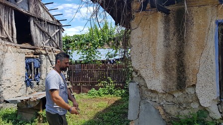 Marius examinează pereţii exteriori ai casei lui Gheorghe