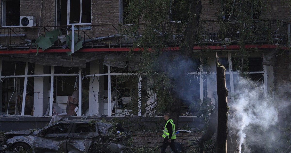 Un ofițer de poliție trece pe lângă o mașină incendiată la locul unei clădiri rezidențiale avariate în urma unui atac cu rachete și drone rusești la Kiev, pe 17 iunie 2025