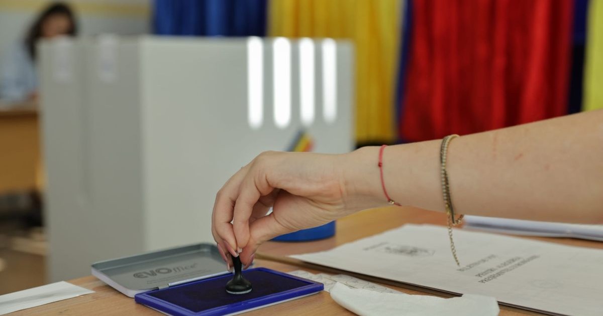 O femeie ia ștampila din tușieră pentru a pune pe buletinul de vot, la alegerile prezidențiale din România, București, 4 mai 2025