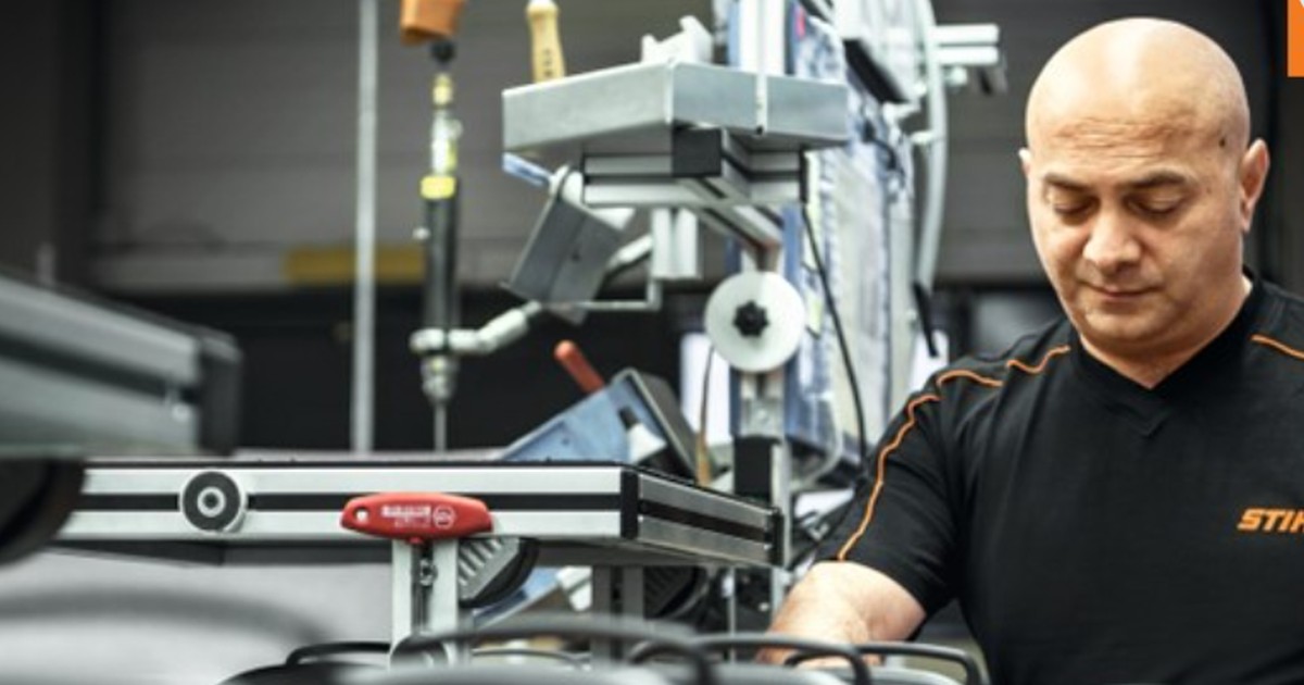 Un muncitor verifică un utilaj pe lina de asamblare a unei fabrici Stihl