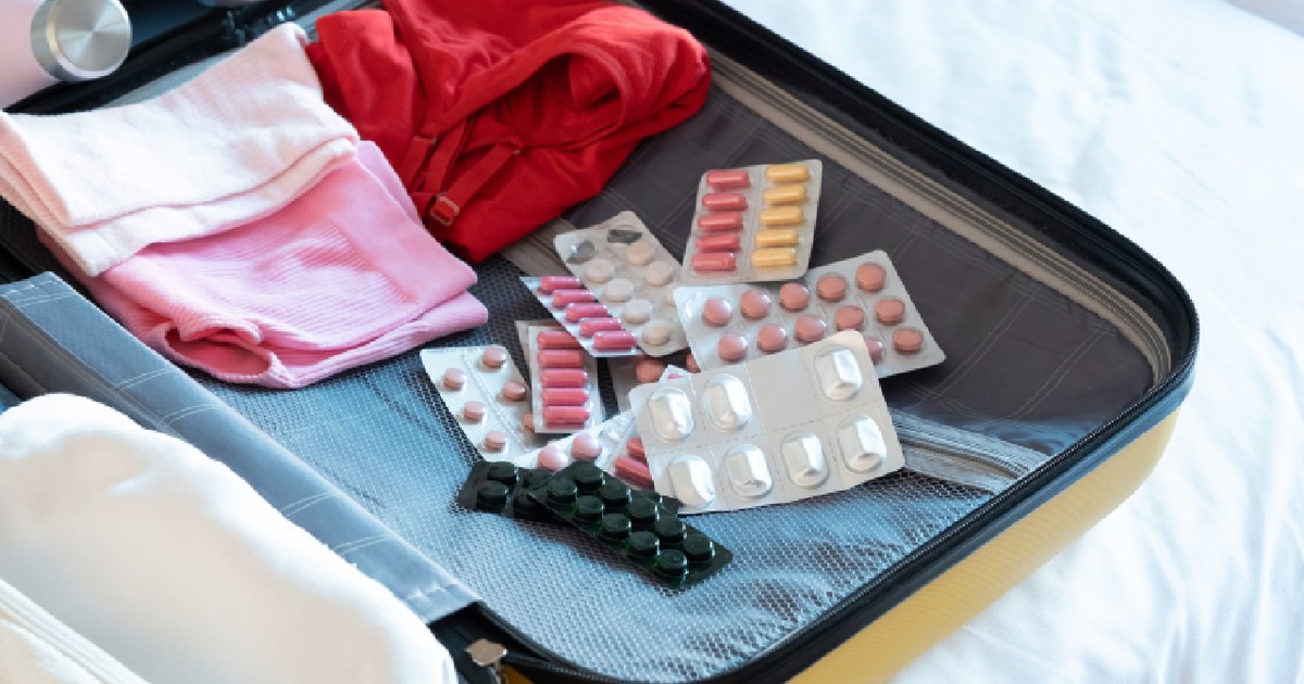 Geamantan galben în care se află mai multe tipuri de medicamente și multe haine