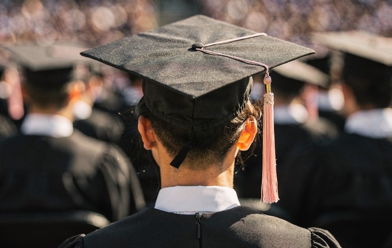Vedere a unui absolvent de facultate care poartă pălărie și robă la ceremonia de absolvire